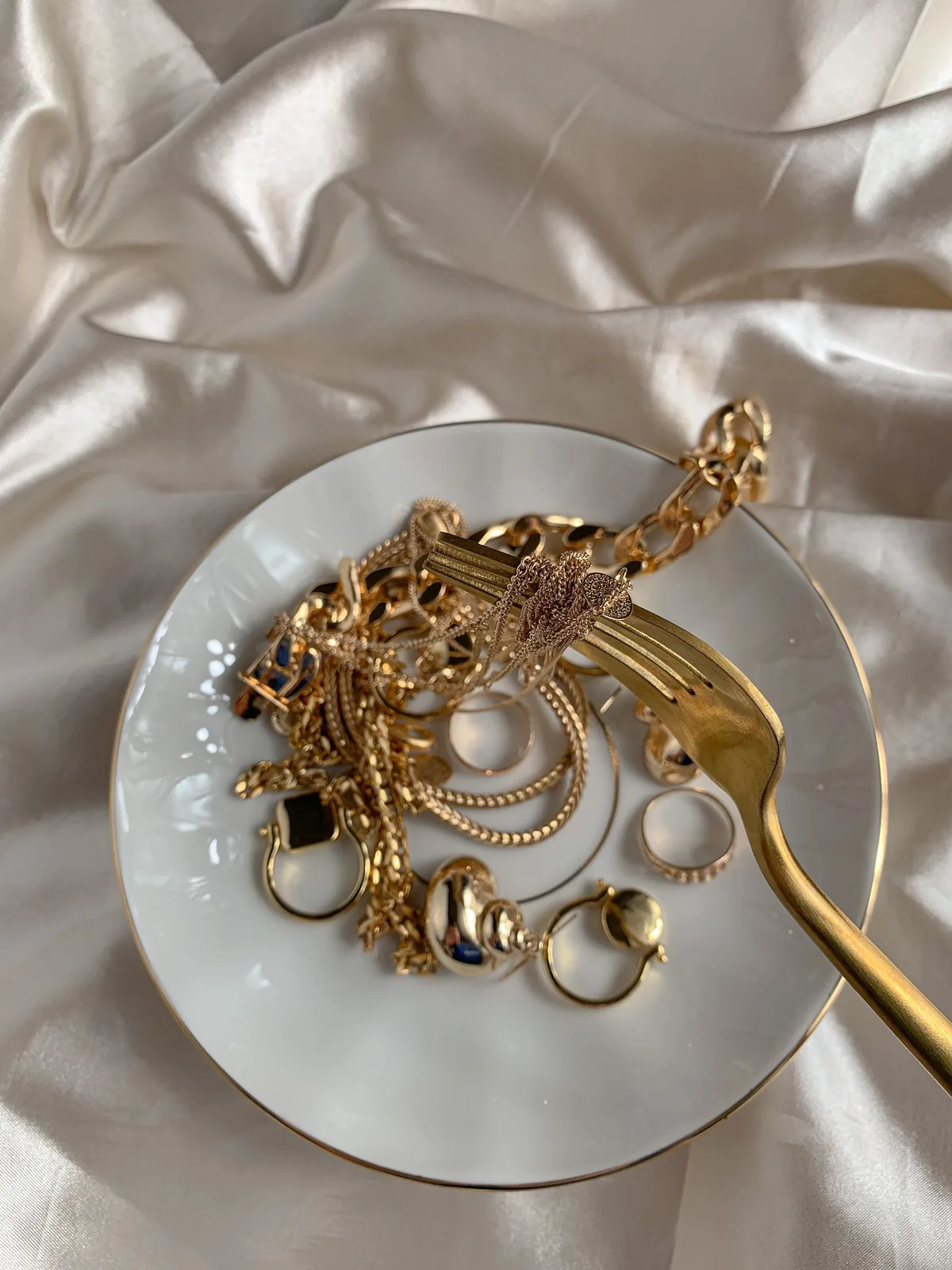 Collares, pulseras, aros y anillos dorados sobre un plato blanco